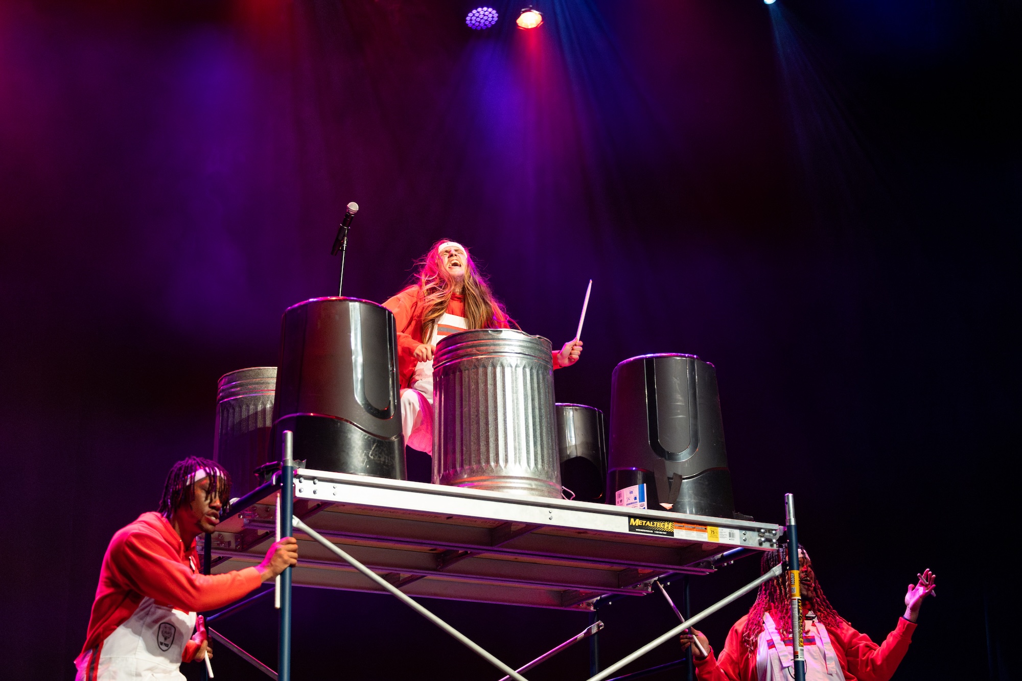 The White Wolf, director of the Pack Drumline, drums on garbage cans on top of a moving scaffold.