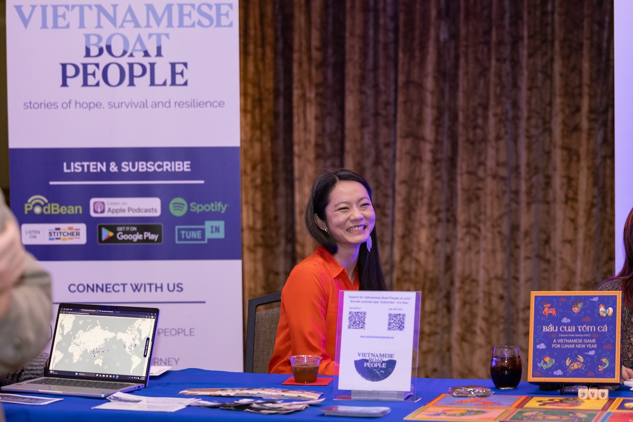 Joyce Hu sits at the Vietnamese Boat People table at the Our Journeys opening event