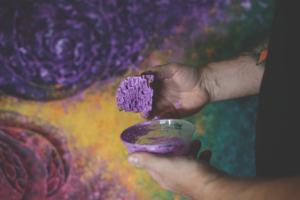 Rob Homan holds a paint-soaked sponge in front of a sculpture