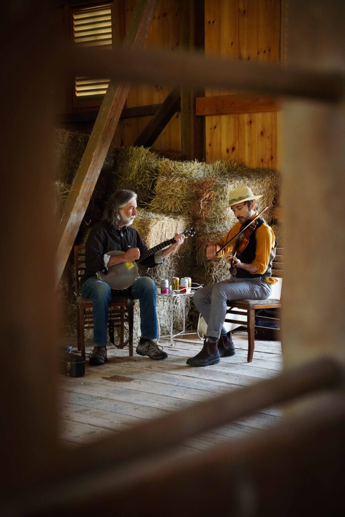 Mark and Jordan Rast perform stringed instruments together in a barn