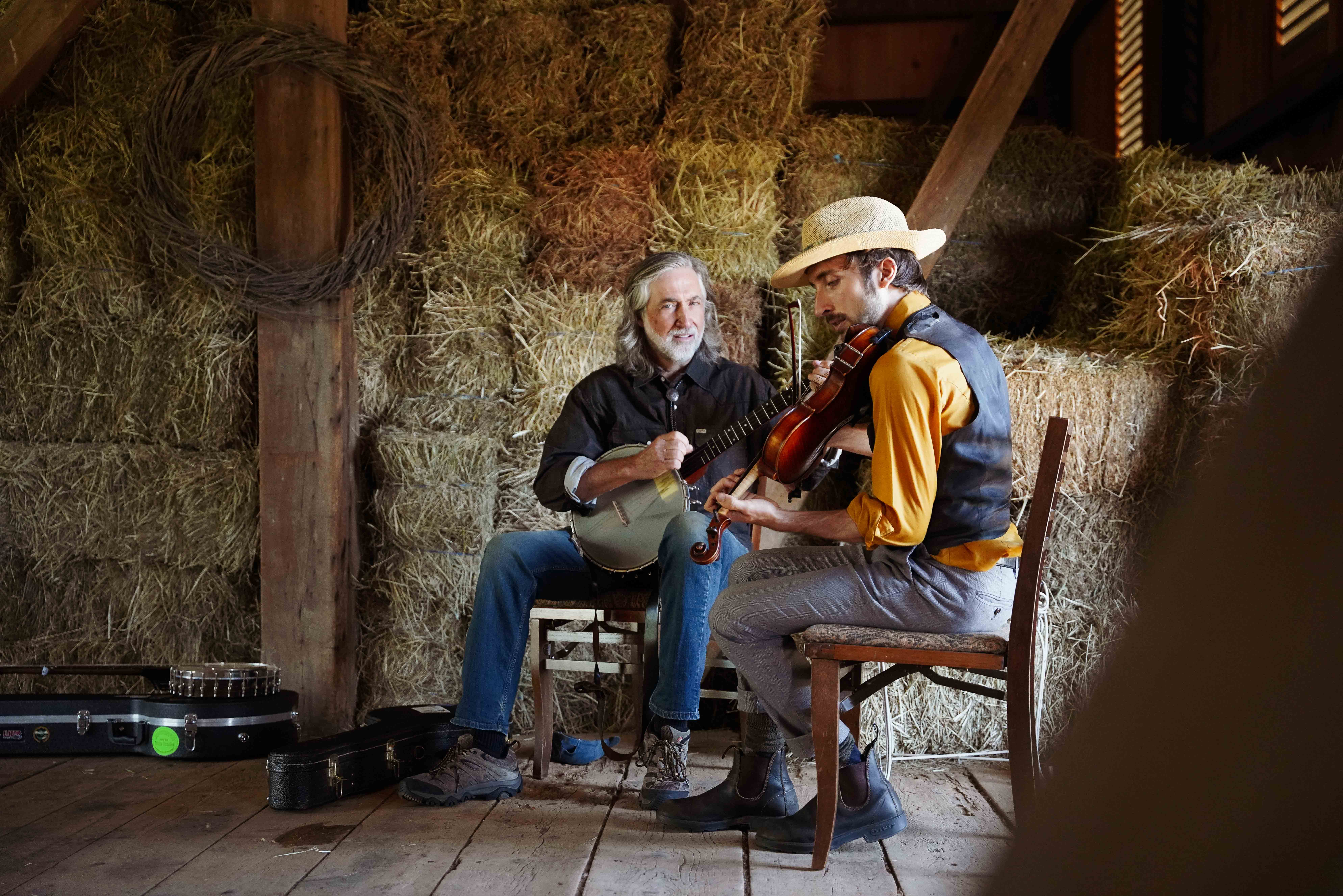 Mark and Jordan Rast perform stringed instruments together in a barn